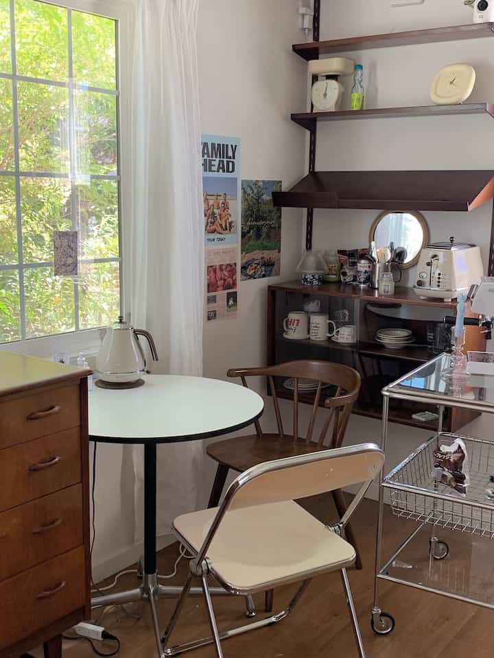 ナチュラルカラーとホワイトのトーンのキッチン、ラウンドカフェテーブルと木製チェストが配置された落ち着いた清潔感のあるインテリア