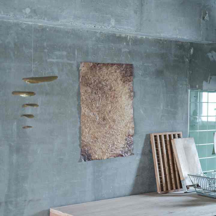 Gray concrete wall kitchen space with natural wood tone cutting boards and vintage poster, featuring a simple industrial vibe