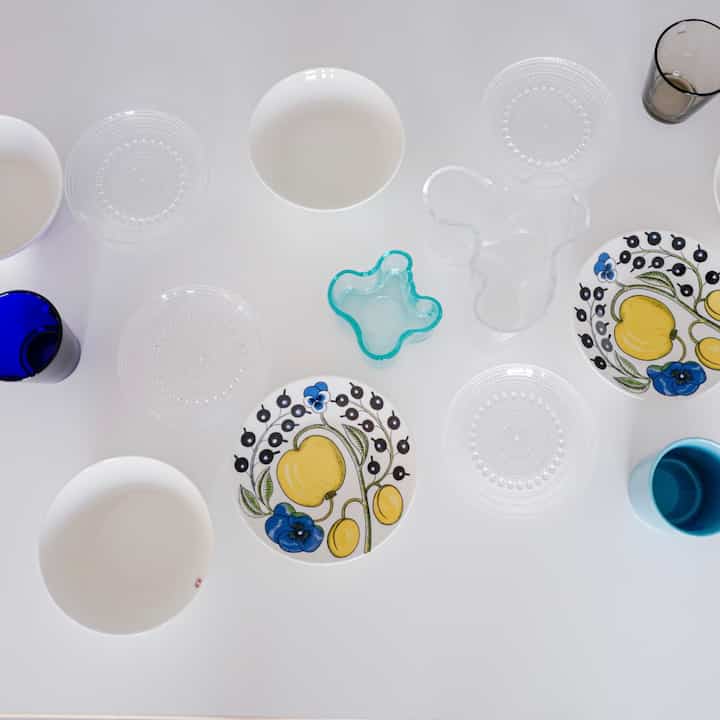 白い背景にノルディックスタイルの皿と透明なグラスが調和して配置されたシンプルな食器セット