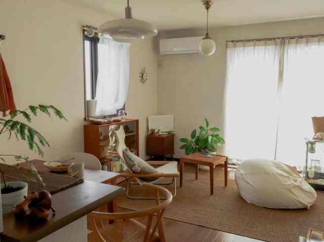 ナチュラルな色調のリビング、木製のアームチェアとビーンバッグ、コーヒーテーブルが配置された落ち着いた雰囲気のあるインテリア