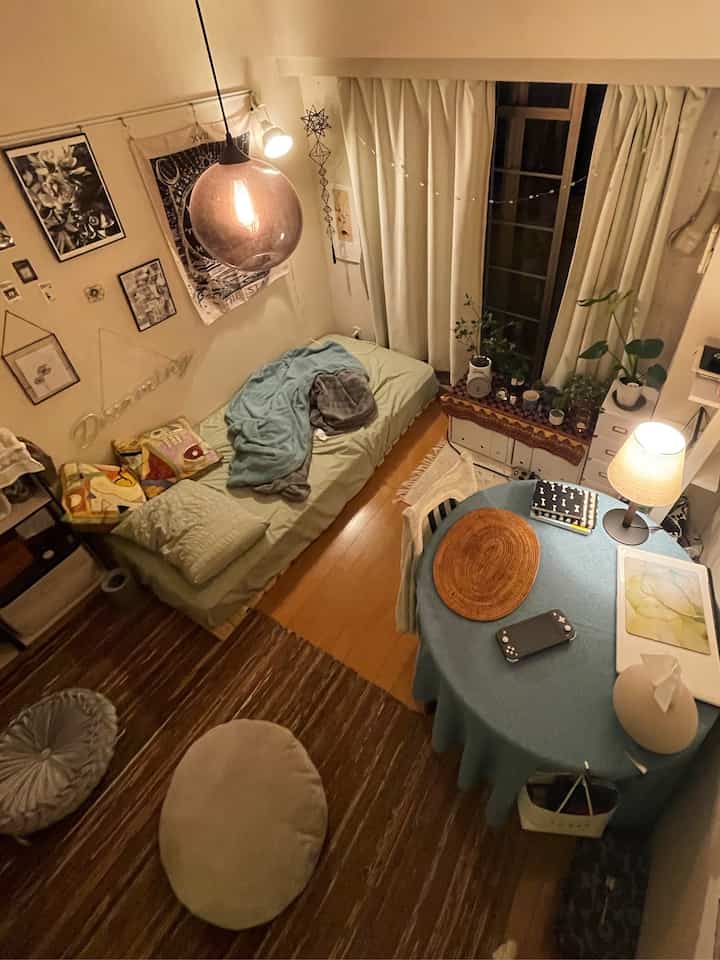 Natural beige and brown toned studio apartment with bed, round dining table, and warm lighting creating a cozy atmosphere