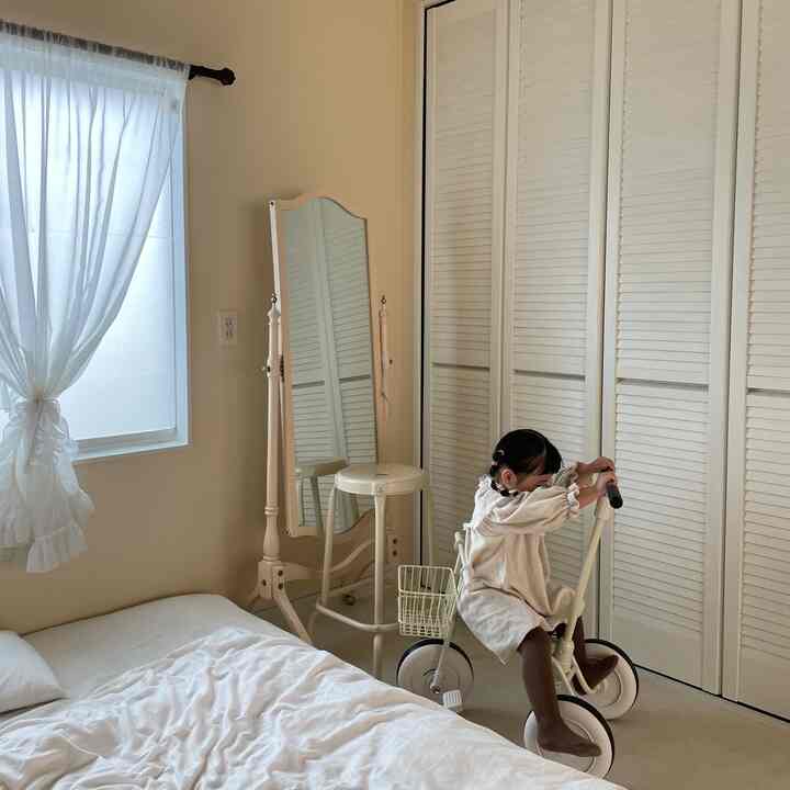 Beige-toned bedroom and kids' room featuring a child riding a beige tricycle, creating a cozy atmosphere