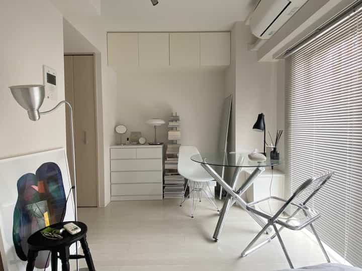 白とグレーのトーンの小さなリビング、透明なガラスのダイニングテーブルとモダンな家具が配置された印象的な空間