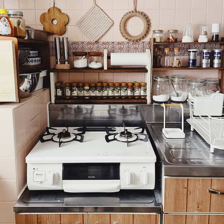 ナチュラルな木目調とステンレスが調和したキッチン、整然と並べられたスパイスラックと調理器具が配置されたコンパクトな空間