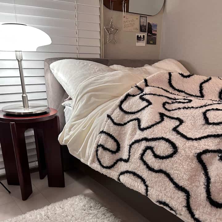 Warm brown and white bedroom featuring a velvet headboard and patterned blanket with cozy atmosphere