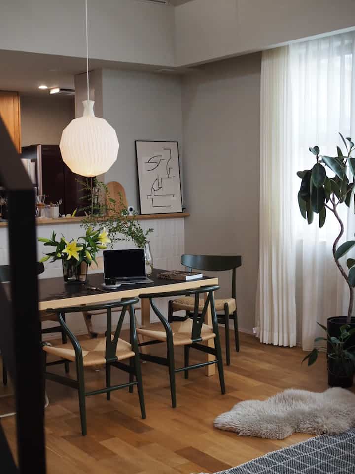 木目調とホワイトのダイニングルーム、ダイニングテーブルとペンダントライト、植物が配置された落ち着いた北欧の雰囲気のあるインテリア