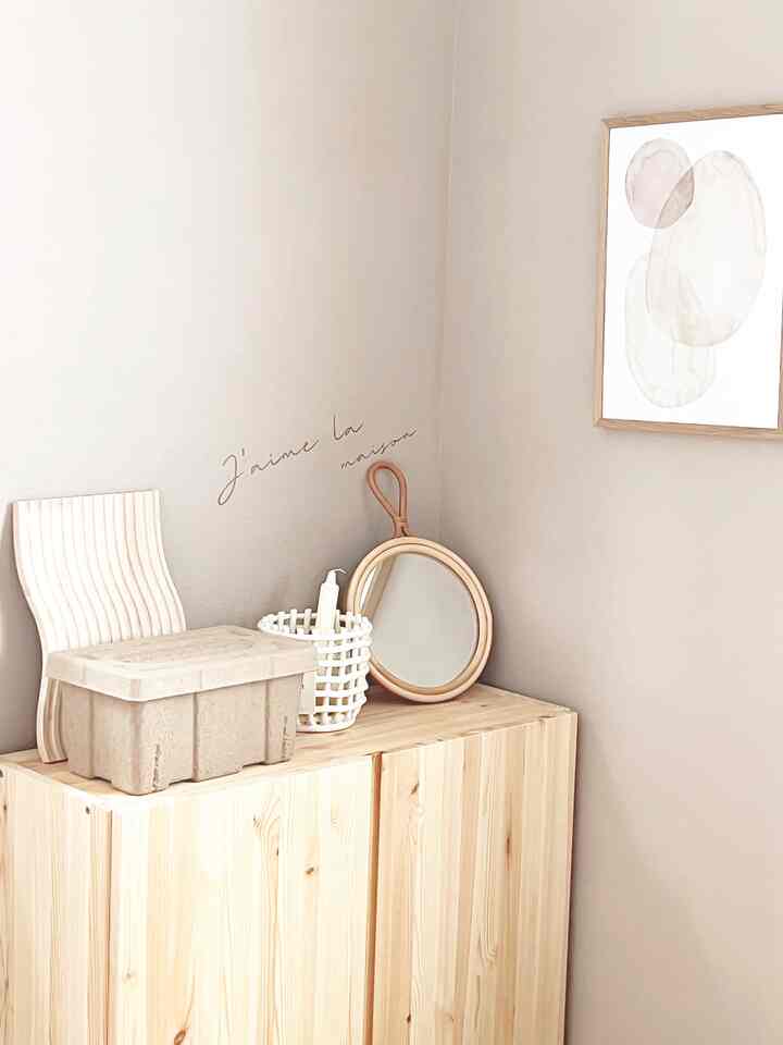 Corner of a simple and natural space featuring a beige-toned storage cabinet and wall decor