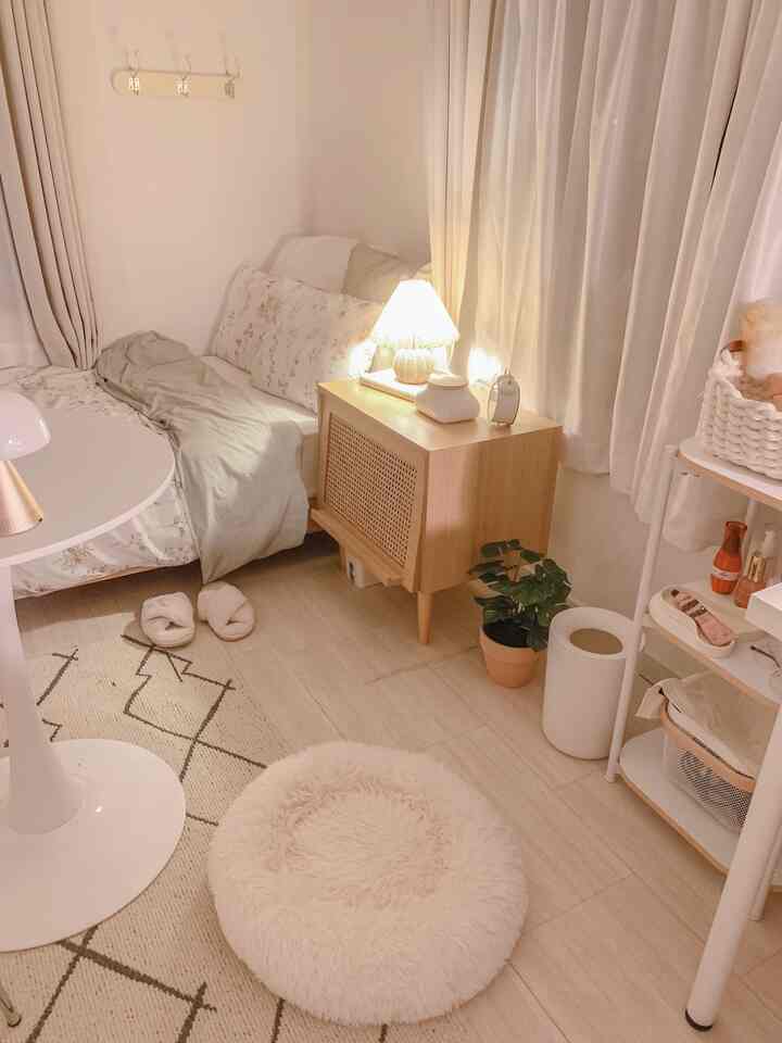 暖かいナチュラル色調の寝室、木製のサイドテーブルとラグが配置された雰囲気のあるインテリア