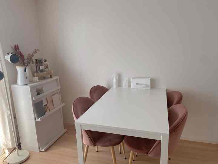 白と茶色のトーンのダイニングルーム、ピンクの椅子が配置されたシンプルで温かみのあるインテリア