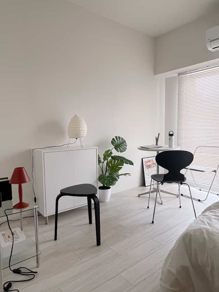 White and black toned 8-tatami studio apartment featuring simple, natural modern furniture and a tidy remote work area