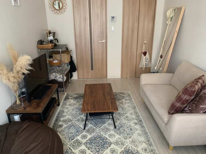 Natural wood tone compact living room featuring a beige sofa and wooden coffee table with cozy ambiance