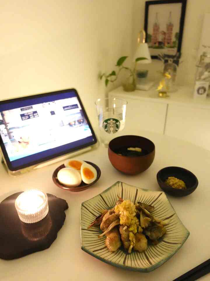 白を基調としたワンルームの空間、丸いダイニングテーブルに料理とタブレット、キャンドルが置かれたシンプルな雰囲気のインテリア