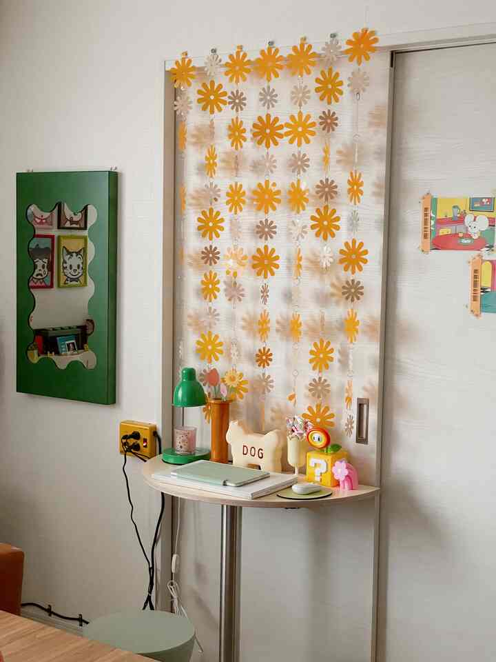 ナチュラルカラーのリビング、コンパクトな半円デスクとグリーンのテーブルランプが配置された雰囲気のあるホームオフィス空間