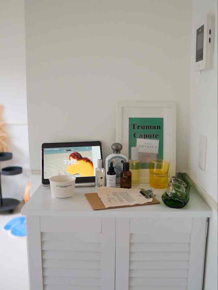 白を基調としたコンパクトなコーナースペース、白い棚の上に小物とタブレットが配置された印象的なモダンなインテリア