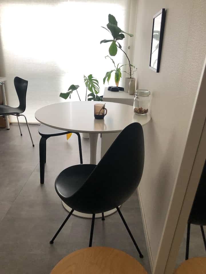 Modern white and black toned studio dining room featuring Drop chairs and a round dining table with a clean aesthetic