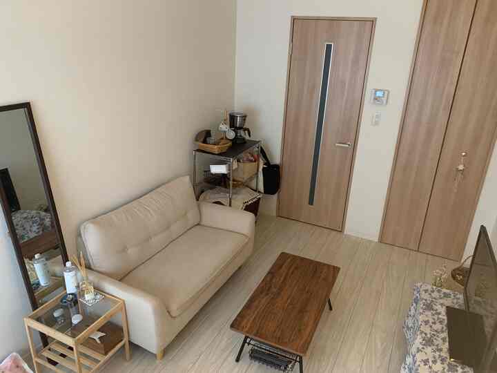 ベージュと木目調の落ち着いたリビング、すっきりとしたソファと木製のセンターテーブルが配置された自然な雰囲気のインテリア