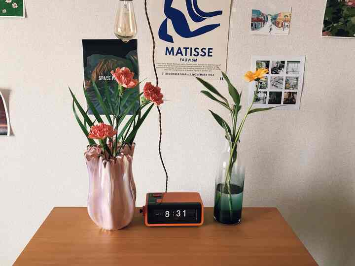 ナチュラルカラーの狭い部屋、壁にマティスのポスター、テーブル上の花瓶と花が配置された雰囲気のあるインテリア