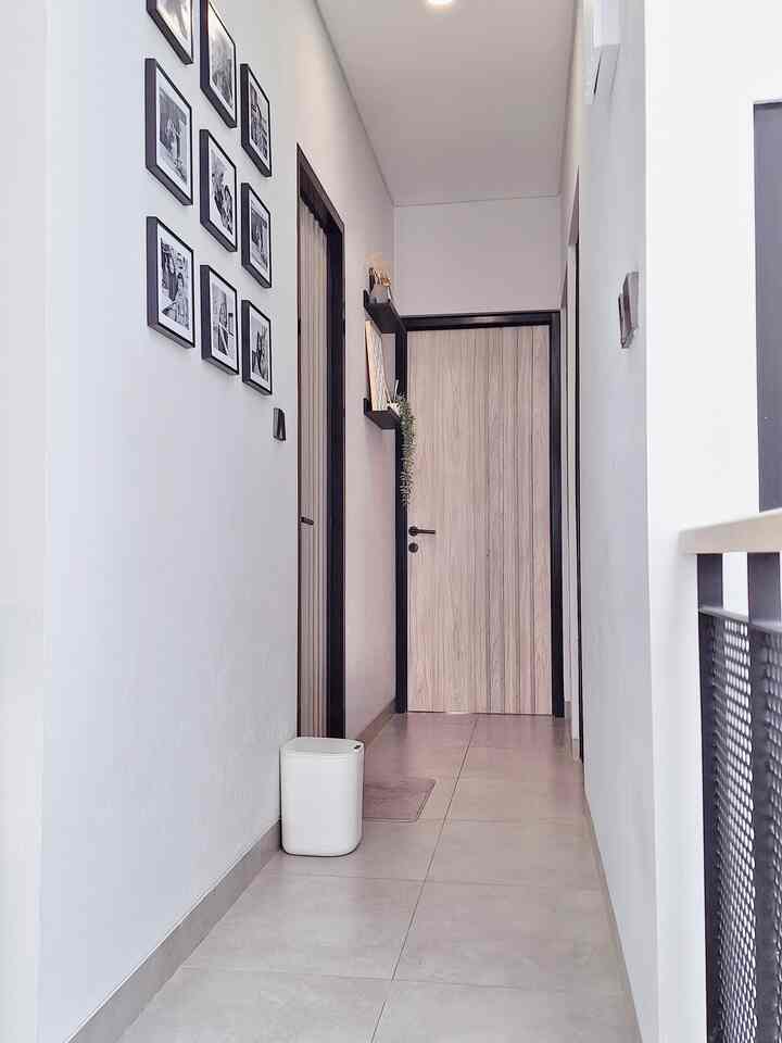 White and gray toned narrow hallway featuring picture frames and shelves with a minimalist feel