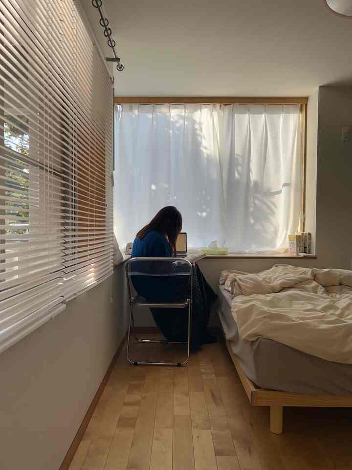 自然光が差し込む白とナチュラルトーンの6畳寝室、窓際にデスクと白いカーテンが配置された雰囲気のある空間