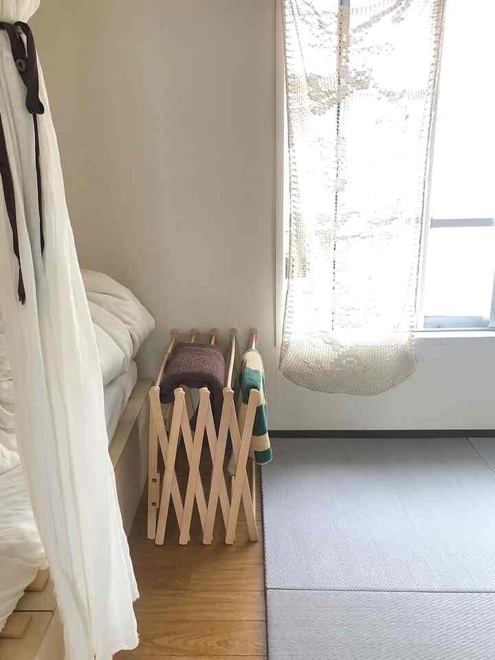 白と木目調の狭い寝室、ベッド横に収納アイデアのウッドラックが置かれた自然な雰囲気のインテリア