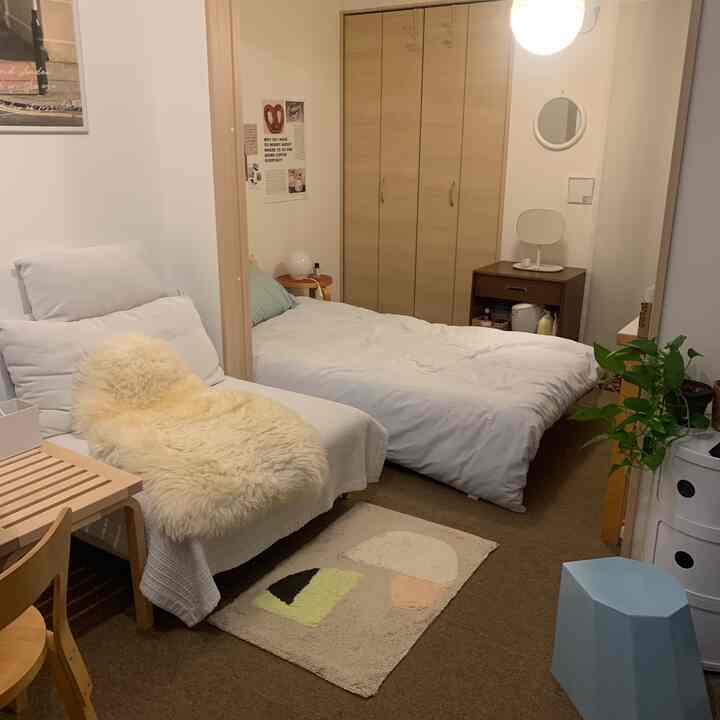 ベージュとホワイトのトーンが特徴的なワンルーム、ソファとベッドが配置された雰囲気のあるインテリア