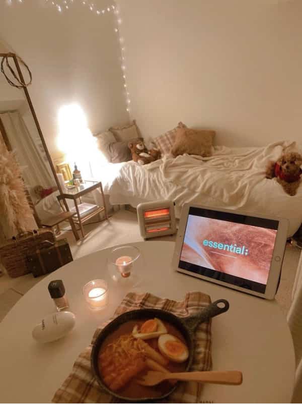 暖かみのあるホワイトとブラウンの寝室、キャンドルと足元ヒーターが配置された雰囲気ある空間