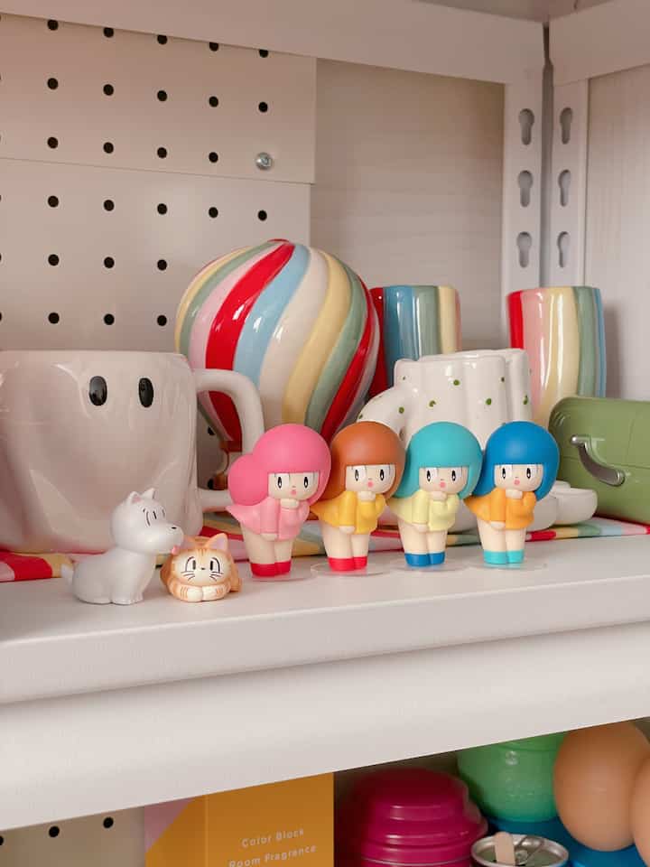 カラフルな小さなフィギュアとマグカップが置かれた棚、かわいいレトロスタイルのインテリア小物