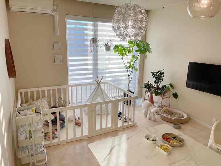 ベージュの色調のリビング、白いベビーサークルに赤ちゃんが遊んでいる印象的な空間