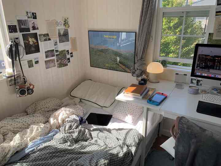 自然光が差し込む白を基調とした6畳の寝室、小さな机とベッドが配置された落ち着いた空間