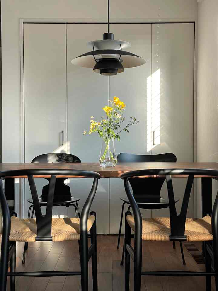 黒と木目調のダイニング、北欧スタイルのYチェアとアリンコチェア、ペンダントライトが織りなす印象的な空間