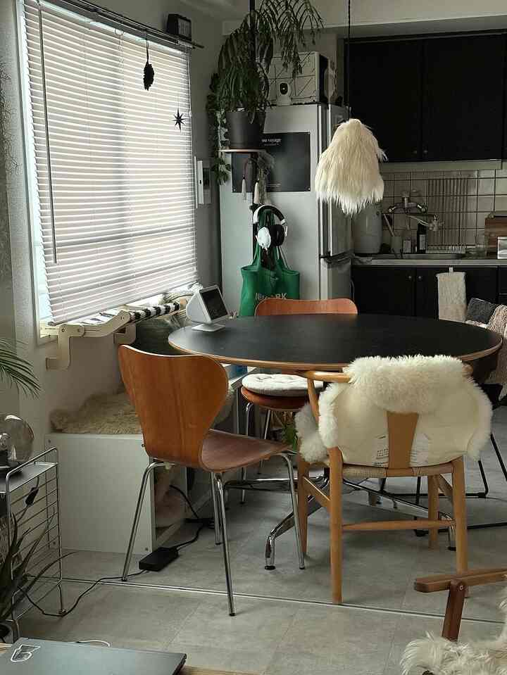 Natural modern living and dining room featuring wood tone chairs and black dining table with cozy white accents
