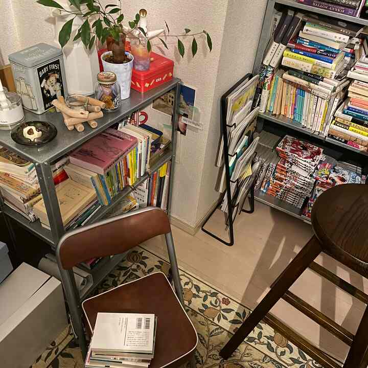 温かみのあるブラウン調のコンパクトな作業空間、折りたたみ椅子と本棚が並ぶ居心地の良い読書スペース