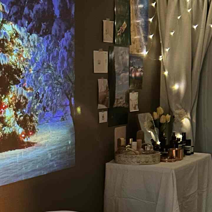 暖かい茶色の壁と白いカーテン、白いテーブルクロスが配置された、クリスマスの雰囲気のある居心地の良いホームシネマ空間