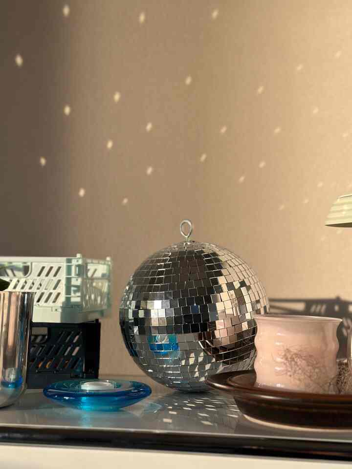 Silver and white tone interior decoration space featuring a mirror ball and pink candle holder with warm ambiance