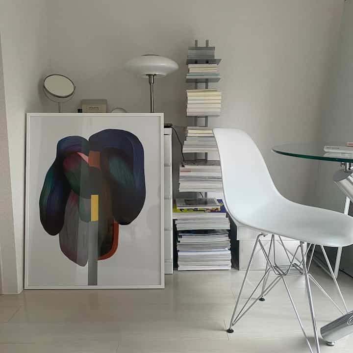 白を基調としたダイニングルーム、大きな抽象ポスターと棚が配置されたシンプルでモダンな雰囲気のインテリア