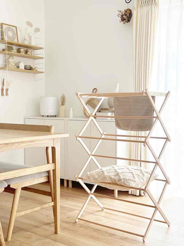 明るいナチュラルカラーの6畳ダイニングスペース、ダイニングテーブルと椅子、木製の物干しラックが配置された清潔感のあるインテリア