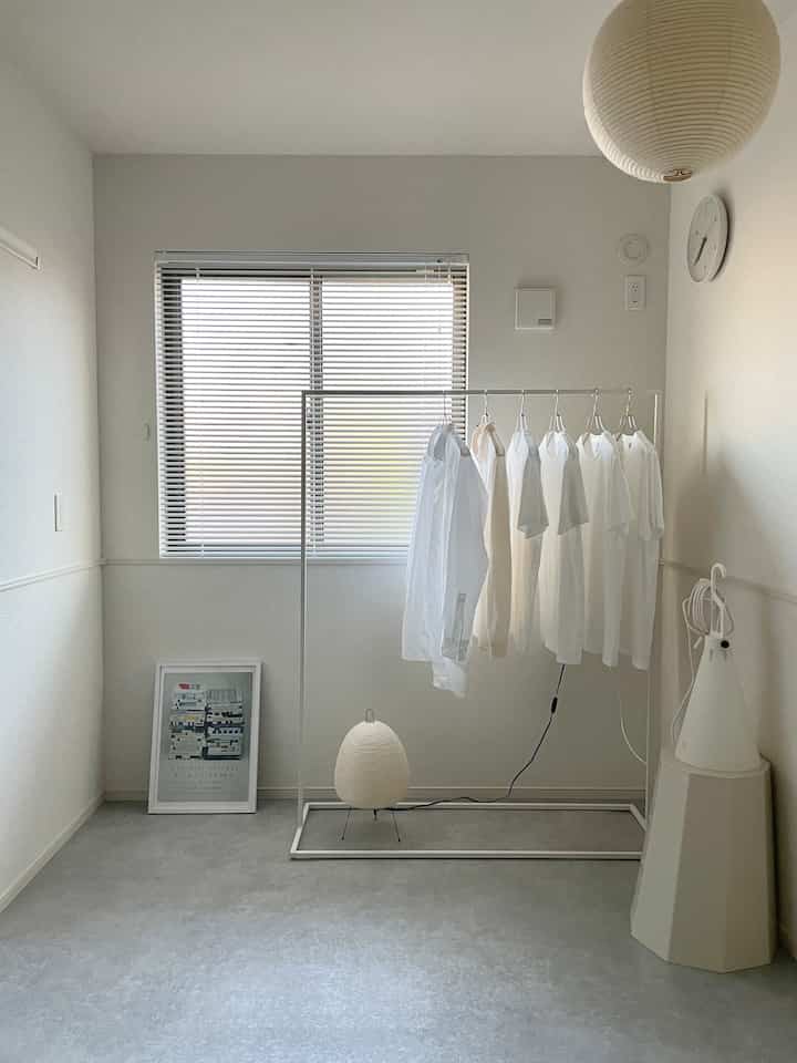 White-toned room with walls and floor, simple clothes rack and lighting creating a bright, spacious atmosphere