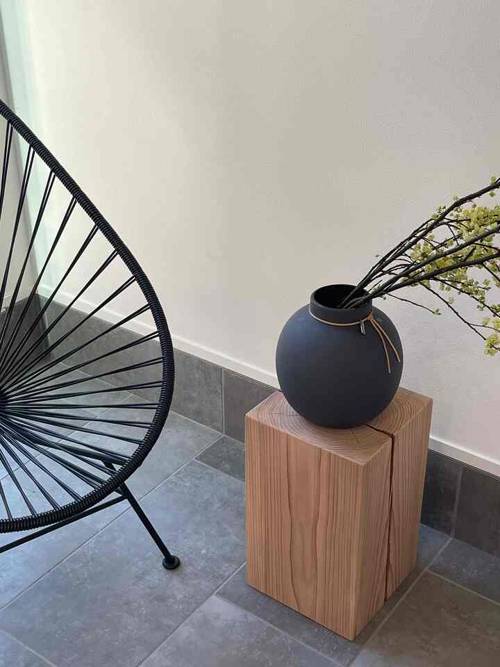 ナチュラルな木目調のサイドテーブルと黒のアカプルコチェアが配置されたシンプルな玄関のインテリア