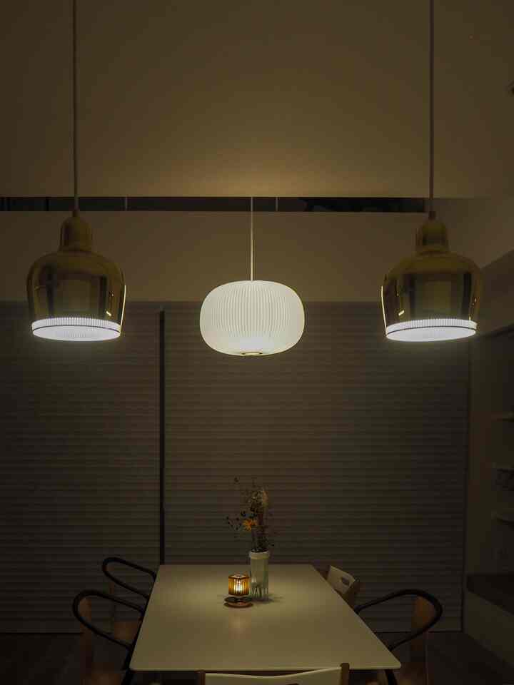 白とゴールドの色調のダイニング、ペンダントライトとダイニングテーブルが配置された落ち着いた空間