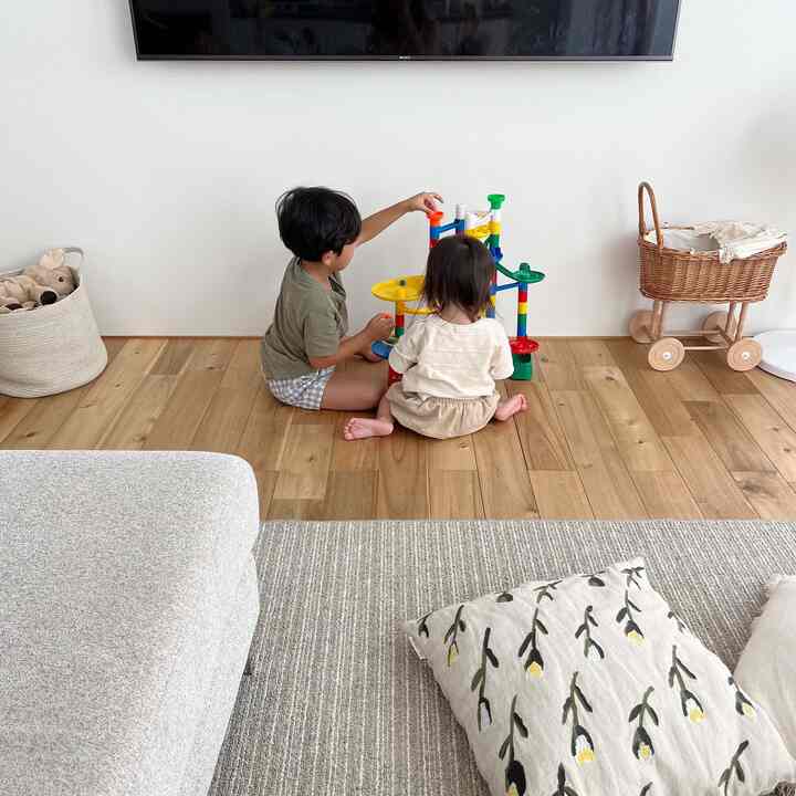 Natural color and wood tone living room with two children playing with toys, featuring a cozy Nordic-style atmosphere