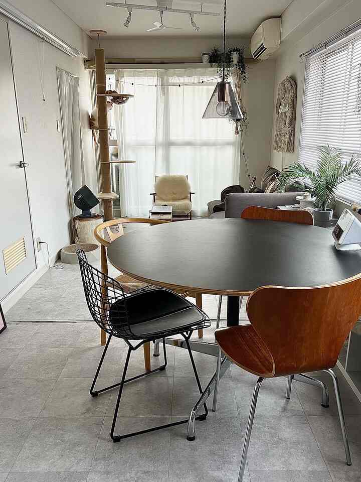 Natural tones with gray and white in a dining room featuring a round dining table and varied chairs in a modern setting