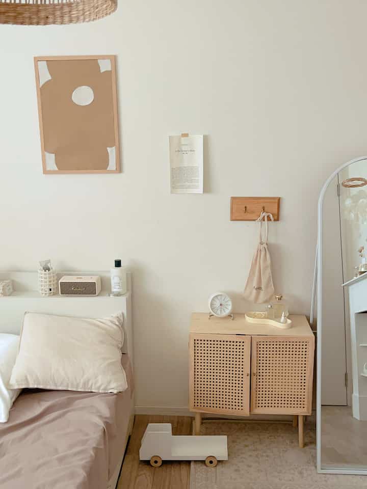 ナチュラルな色調の寝室、ベージュの寝具と木製ナイトテーブル、全身鏡が配置された落ち着いた雰囲気の空間