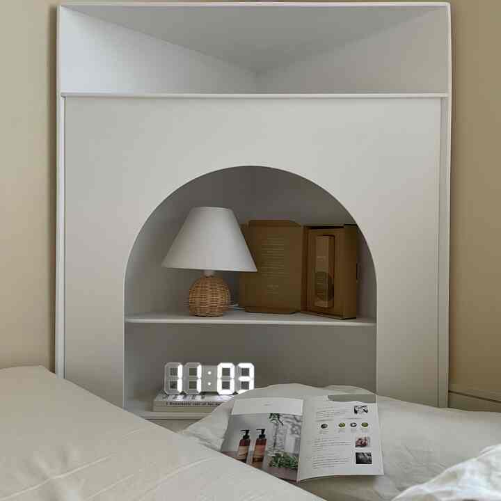 白とナチュラルカラーの寝室、コーナー収納棚とラタンのランプが配置されたモダンな雰囲気のインテリア