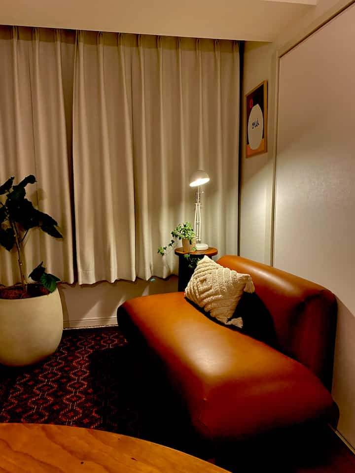 Natural living room with brown leather sofa and beige curtains in a compact space