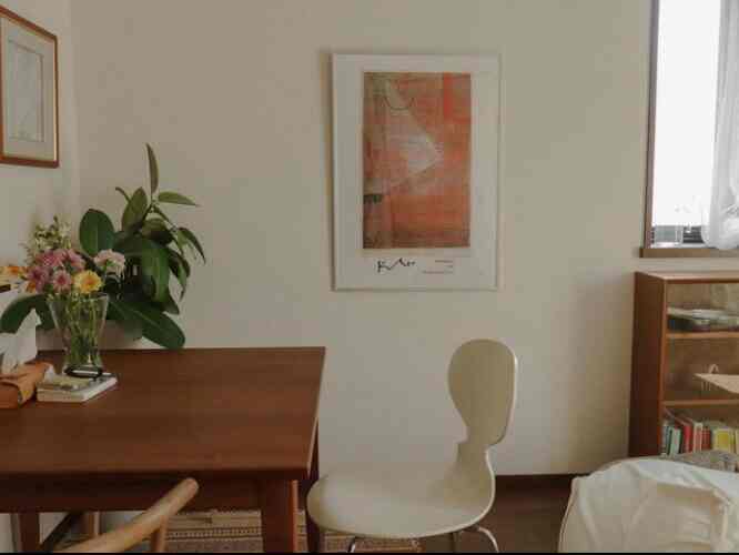 Wood tone living room featuring vintage poster, wooden dining table and chairs with plants creating a natural atmosphere