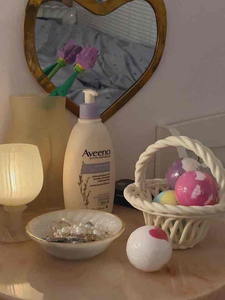 ホワイトとゴールドの色調のバスルーム空間、可愛らしいバスボムとスキンケア用品が配置された温かみのあるインテリア