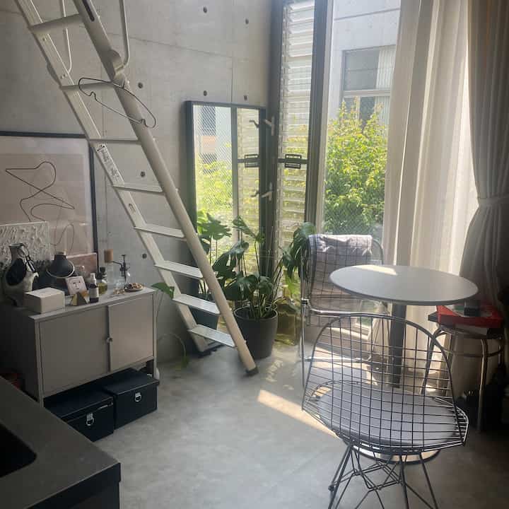 白とグレーのトーンでまとめられたインダストリアルスタイルのダイニング空間、コーナーに配置されたキャビネットとはしごが実用的でモダンな雰囲気を演出