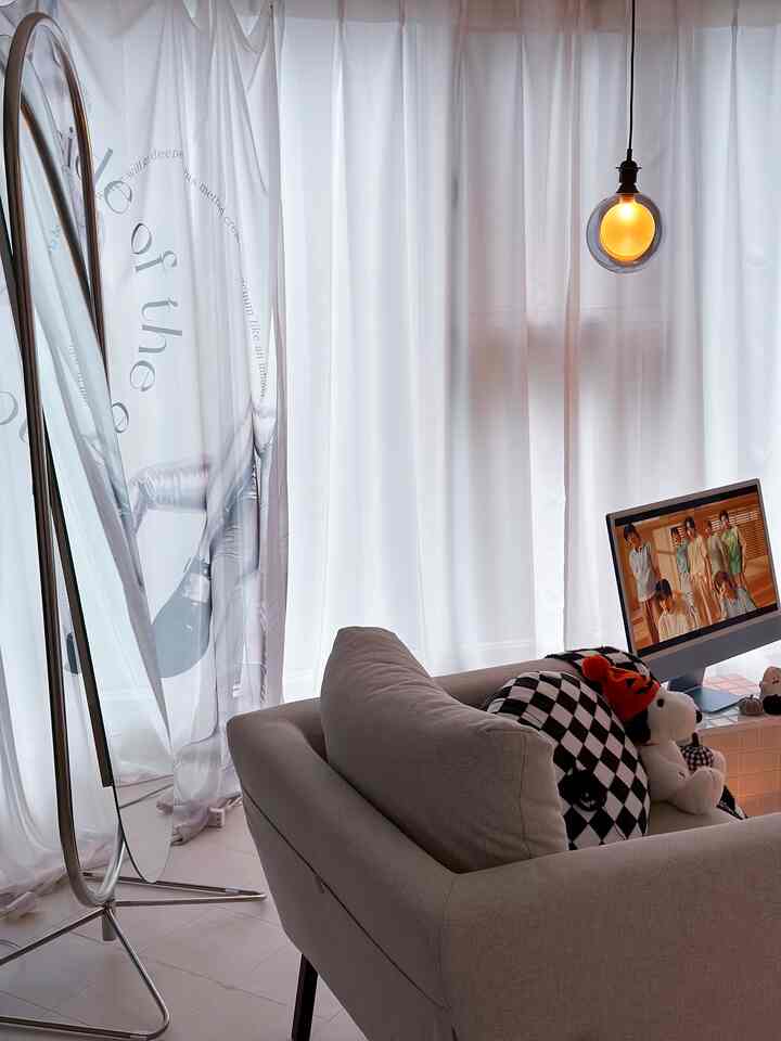 白とシルバーのトーンのモダンなホームオフィス、グレーのソファと温かみのあるLED電球が配置された雰囲気のある空間