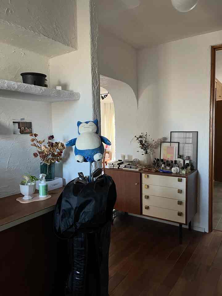 白い壁と茶色の木製家具が配置された広々とした玄関、ゴルフバッグと装飾品が調和したナチュラルな雰囲気のインテリア