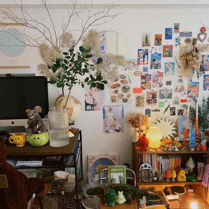 Natural-toned home office featuring a smoke tree plant and a wall filled with various artworks creating a cozy atmosphere